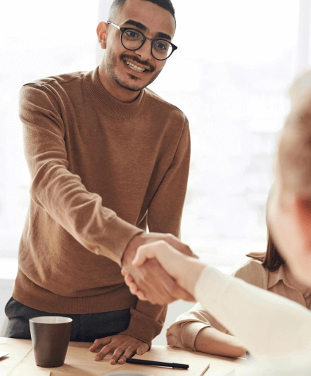 A smiling professional from Gregory Abrams Davidson Solicitors shaking hands with a client during a legal consultation.